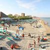 Spiaggia affollata con persone, ombrelloni e mare calmo sotto un cielo sereno.