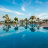 Piscina all'aperto con palme e cielo azzurro.