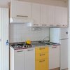 Cucina compatta con mobili bianchi e gialli.