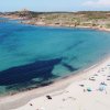 Una spiaggia affollata con ombrelloni colorati, sabbia bianca e mare azzurro.