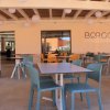 Ristorante all'aperto con sedie colorate e tavoli quadrati sotto una copertura con sfere decorative.