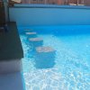 Piscina con gradini sommersi e bordo verde.