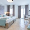 Camera da letto con letto matrimoniale, cuscini azzurri, TV a parete e scrivania con sedia.