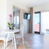 Soggiorno con tavolo rotondo, TV a parete e accesso a un balcone.