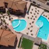 Vista aerea di un complesso con piscine, ombrelloni e edifici con tetti in tegole.