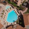 Vista aerea di una piscina circondata da lettini e ombrelloni.