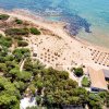 Vista aerea di una spiaggia con ombrelloni e mare azzurro.
