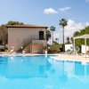 Piscina con sdraio e un edificio a due piani sullo sfondo.