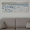 Divano beige con quadro di una spiaggia sopra.