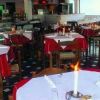 Ristorante elegante con tavoli apparecchiati, candele accese e tovaglie rosse e bianche.