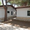 Due bungalow bianchi con pareti in pietra e alberi.