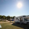 Un camper parcheggiato su un prato sotto il sole splendente.