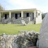 Edificio in pietra con scale e prato verde, incorniciato da rocce.