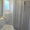 Bagno compatto con doccia, lavandino, e specchio.