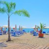 Spiaggia con sedie a sdraio e ombrelloni, palme.