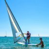 Persona che pratica windsurf assistita in mare.