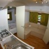Cucina e salotto con divano beige e tende verdi.