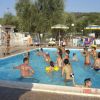 Gruppo di persone che giocano e nuotano in una piscina luminosa con ombrelloni intorno.