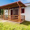 Piccola casa bianca con veranda in legno e giardino curato.