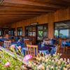 Ristorante in legno con tavoli apparecchiati e fiori in primo piano.