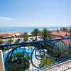 Vista dal balcone sul mare e piscina circondata da palme.