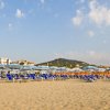 Spiaggia con sdraio e ombrelloni blu.