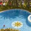 Piscina a forma di fagiolo circondata da sdraio e palme.