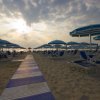 Spiaggia con ombrelloni a strisce blu al tramonto.