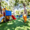 Parco giochi con scivolo e giochi a molla su erba.