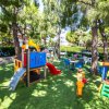 Giardino con giochi e tavolini tra gli alberi.