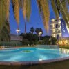 Piscina illuminata, palme e edificio a più piani di notte.