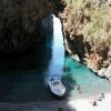 Barca e persone su una spiaggia in un'insenatura rocciosa.