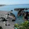 Spiaggia con rocce e ombrelloni, mare calmo.