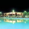 Piscina illuminata di notte con persone sotto un padiglione.