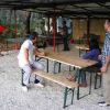 Persone in piedi e sedute su tavoli da picnic in un'area coperta all'aperto.