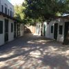 Cortile pavimentato tra edifici bianchi con persiane verdi.