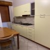 Cucina con mobili chiari e tavolo in legno.