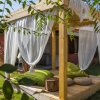 Pergola in legno con tende bianche e cuscini verdi.