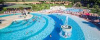 Grande piscina con fontana centrale, circondata da persone e lettini.