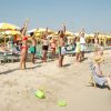 Gruppo di persone in costume fa stretching sulla spiaggia.