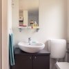 Bagno con lavabo moderno, specchio sopra, WC e asciugamano appeso.