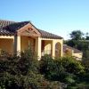 Casa con tetto in tegole, circondata da arbusti verdi.