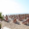 Spiaggia sabbiosa con lettini e ombrelloni colorati in fila.