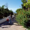 Due bambini camminano lungo un vialetto alberato e fiorito.