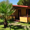 Bungalow giallo con veranda e palme intorno.