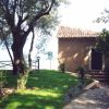 Una piccola casa di pietra con tetto di tegole, circondata da alberi e prato verde.