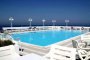 Una piscina su una terrazza con lettini e vista sul mare.
