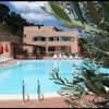 Piscina scoperta con edifici e ombrelloni arancioni.