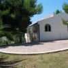 Casa bianca tra alberi e sentiero piastronato.