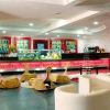 Un elegante bar moderno con arredi bianchi e rossi, e un lungo bancone illuminato.